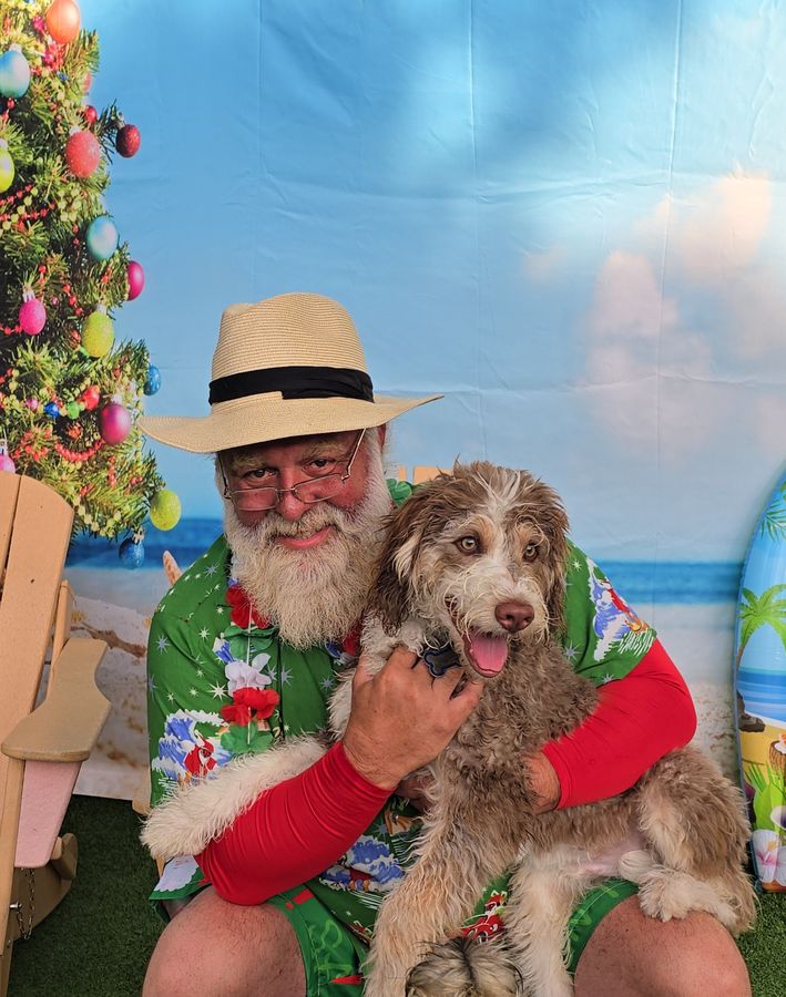 Summer Santa in a tropical shirt hugging a happy doodle